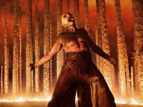 28 Years Later: The Bone Temple: Ralph Fiennes among a bone memorial, surrounded by fire.
