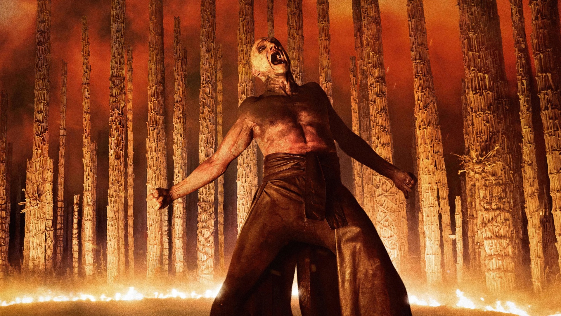 28 Years Later: The Bone Temple: Ralph Fiennes among a bone memorial, surrounded by fire.